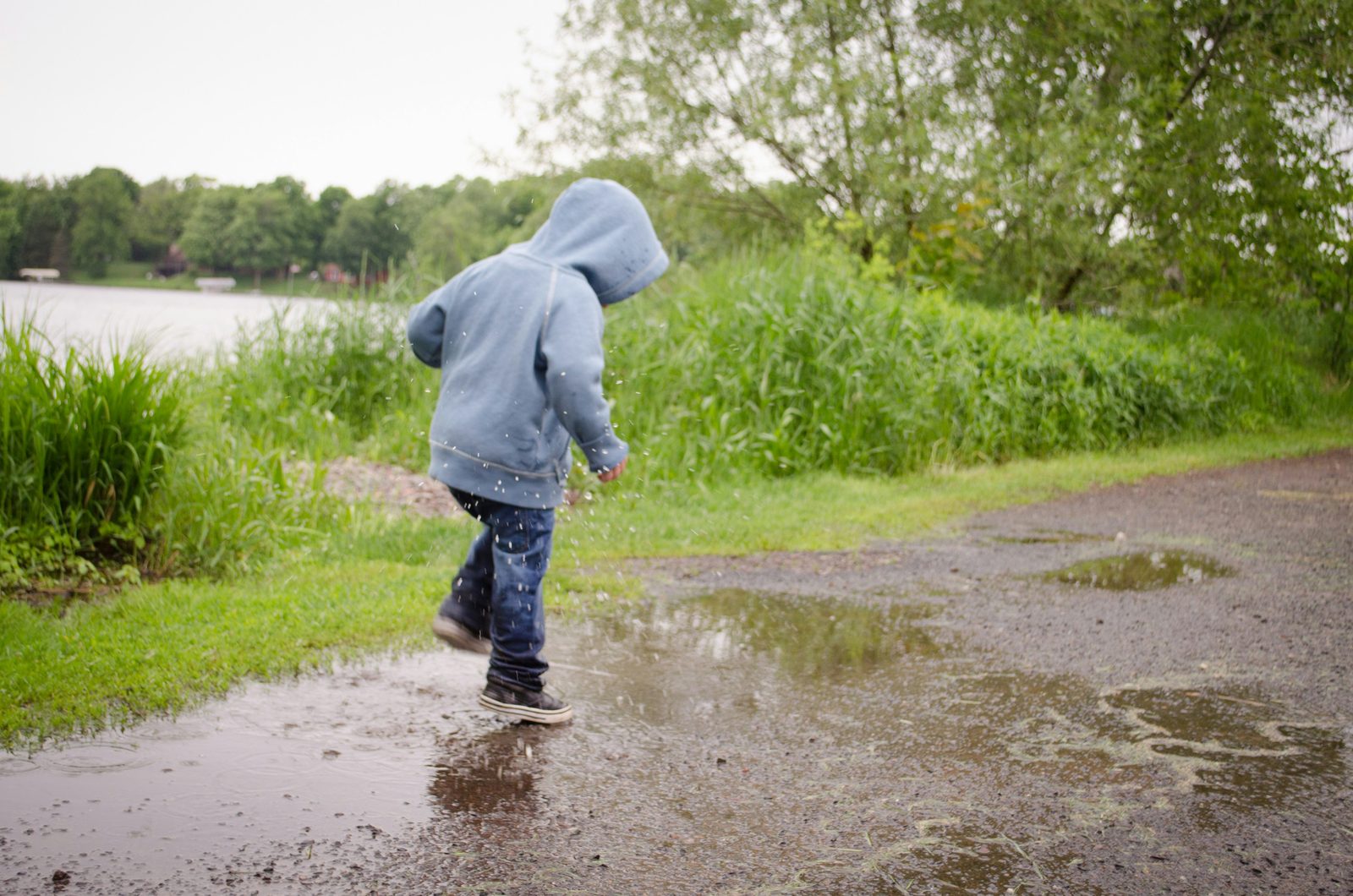 Child in a hooded jacket splashing through a rain puddle: herbal support for colds and flu in Waimea and Kona, Hawaii