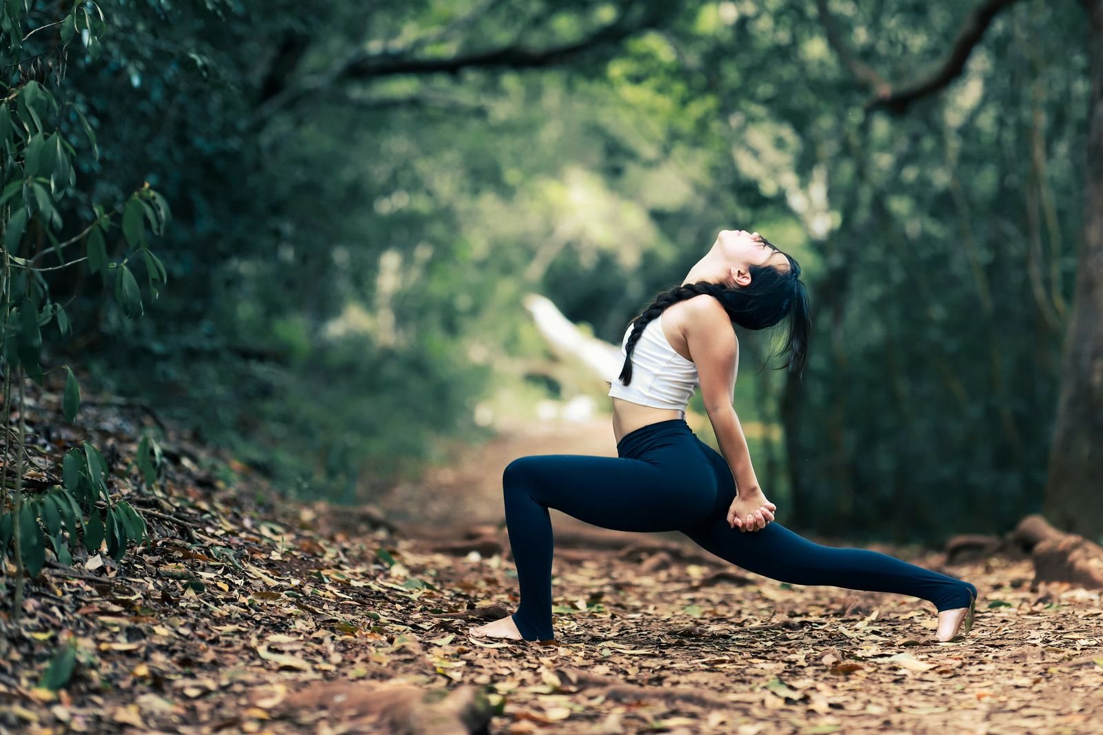 Woman stretching in a lunge on a forest trail: acupuncture for sciatica in Waimea and Kona, Hawaii