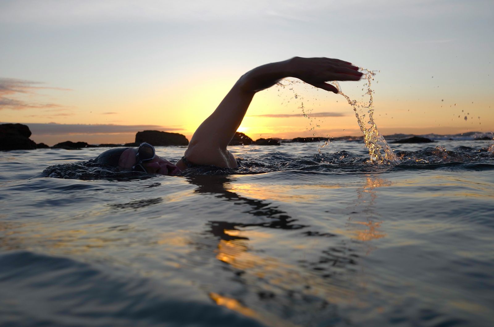 Ocean swimmer reaching forward mid-stroke at sunset: acupuncture for shoulder pain in Waimea and Kona, Hawaii
